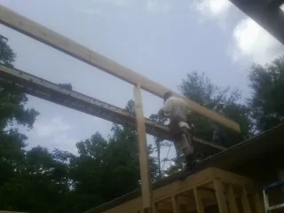 Carpenter setting a ridge beam over a new addition frame — Ice Dam Removal by Roofing Brothers in Temple