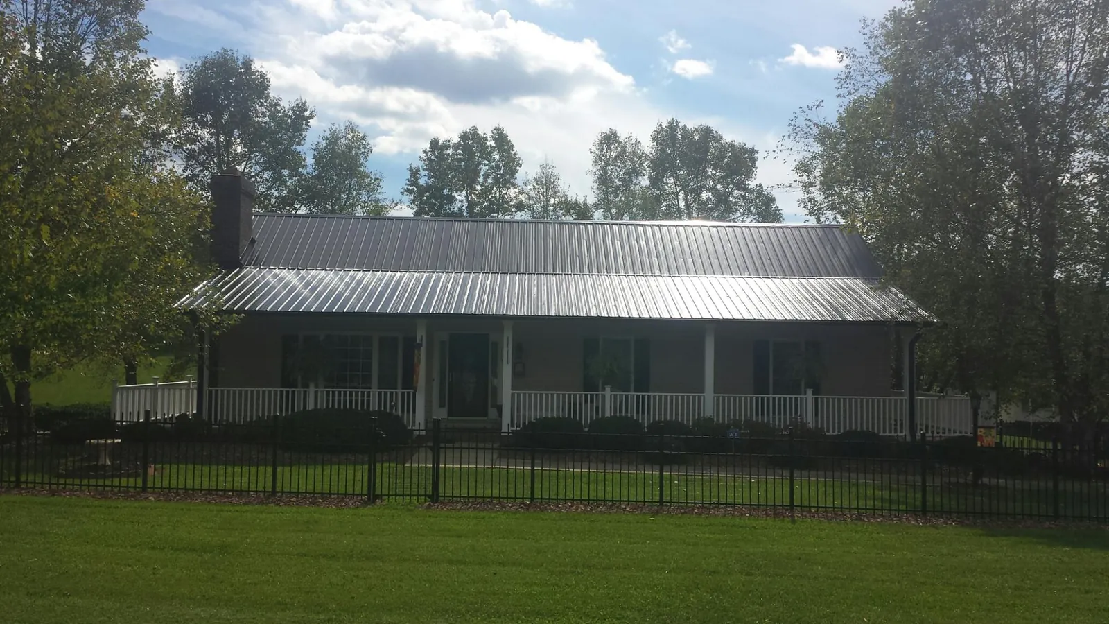 Gray metal roof on a brick ranch with a full width front porch — Gutter Guard Installation work by our crew in Temple