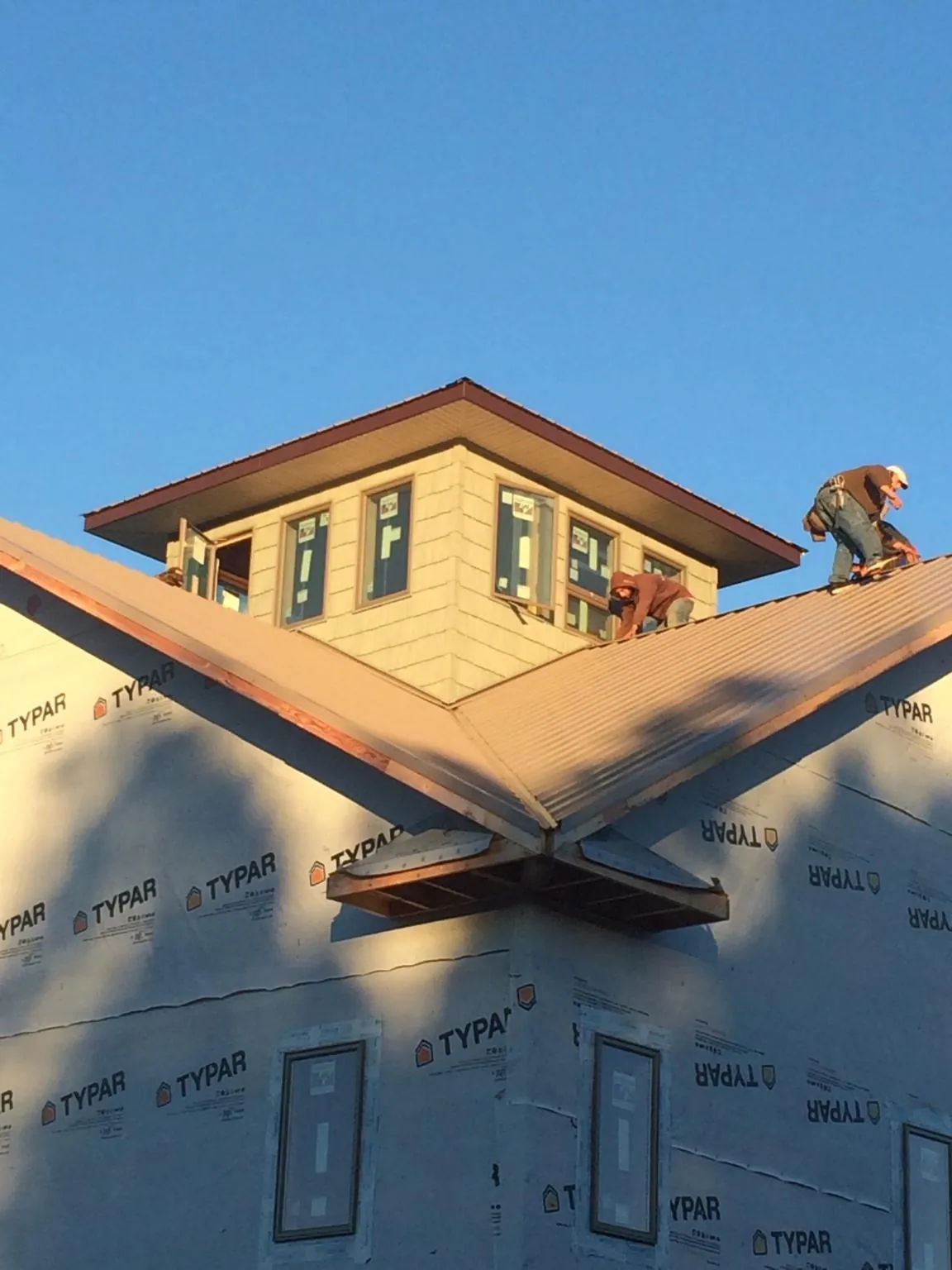 Roofers working around a rooftop cupola on a new metal roof at sunset — Roof Waterproofing in Temple by Roofing Brothers